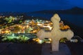 White cross over colorful night view of traditional Greek small town or village by seafront, Plaka, Milos island Royalty Free Stock Photo