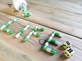 White-green capsules from the jar written the word Life on the table. Next to the dice are two sixes.