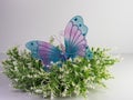 White and green floral wreath with a purple and blue mesh decorative butterfly with gemstones sitting on top with a white