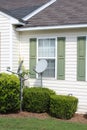White and green house front with two satellite dishes in the front yard between the shrubs Royalty Free Stock Photo