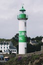 White and green lighthouse with village. Brittany, France