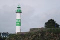 White and green lighthouse with village. Brittany, France