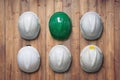 White and green safety hard hat hang on wooden wall