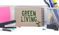 On a white-green surface, a piece of paper, a pen and a notepad with the text - Green Living