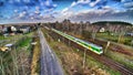 White and green train passing through small village during sunny evening. Royalty Free Stock Photo