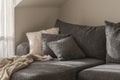 White and grey textured decorative pillows, cozy knitted blanket on a .dark grey sofa. Wabi-sabi interior details for decoration. Royalty Free Stock Photo
