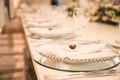 WHITE GROOM AND BRIDE WEDDING TABLE AT IMPRESSIVE COLOURFUL VENUE WITH BEAUTIFUL GREEN FLORAL DECORATION, WINE GLASSES, CRYSTAL PL Royalty Free Stock Photo