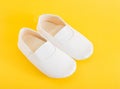 White gym shoes for children on a yellow background. Concepts for comfortable and light indoor shoes and sports, ballet shoes