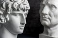 Gypsum copy of ancient statue Augustus and Antinous head on dark textured background. Plaster sculpture mans face.