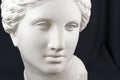 White gypsum copy of ancient statue Venus head on a black background. Plaster sculpture woman face.