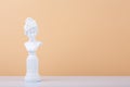 White gypsum statue on white table against beige background with copy space