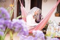 White hair diversity senior woman relax on an hammock in the garden at home reading a paper book and enjoying the quaity of