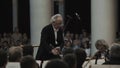 White-haired kapellmeister directing string orchestra in classic concert hall