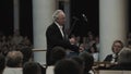 White-haired kapellmeister leading string orchestra in classic concert hall