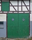 White half-timbered wall with large green wooden barn door and smaller green wooden door on the second floor Royalty Free Stock Photo