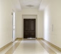 White hallway with marble floor and brown door