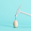 White hammer hitting on white egg on blue background Royalty Free Stock Photo