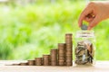 White hand man holding coin to putting in Jar or glass bottle for saving with green background. Saving money, Saving concept Royalty Free Stock Photo