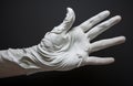 White hand sculpture in an open palm against a solid black background