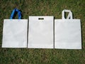 2 white handle loop Eco bags, 1 non woven fabric d cut bags on grass