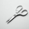 White-handled scissors with stainless steel blades placed on a white surface. Royalty Free Stock Photo