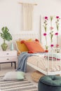 White handmade macrame above above single metal bed with colorful pillows and patterned duvet, real photo