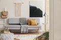 White handmade macrame above grey comfortable sofa with orange pillows and warm blanket, real photo with mockup on the empty wall