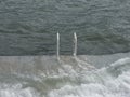 White handrails from cement beach to stormy sea water front view