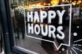 White `happy hours` sign on restaurant window with beautiful bokeh balls in the background