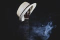 White hat hangs on the smoking guitar fretboard. acoustic musical instrument. strings on the guitar neck