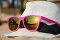 White hat on a wooden pier with fashionable pink sunglasses and reflection Royalty Free Stock Photo