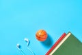 White headphone and old books, toy basketball ball on blue background Royalty Free Stock Photo