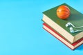 White headphone and old books, toy basketball ball on blue background Royalty Free Stock Photo