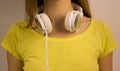 White headphones close-up hanging on the neck of the young girl in a yellow T-shirt Royalty Free Stock Photo