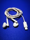 White headphones for a smartphone or an MP3 player with loud and quiet switch on blue background Royalty Free Stock Photo