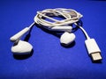 White headphones for a smartphone or an MP3 player with loud and quiet switch on blue background