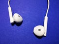 White headphones for a smartphone or an MP3 player with loud and quiet switch on blue background