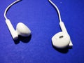 White headphones for a smartphone or an MP3 player with loud and quiet switch on blue background