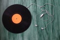 White headphones with wire and vinyl discs on an green background. Retro technique for playing music. Royalty Free Stock Photo