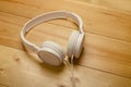 White headphones on wooden table. Modern headphone with cable