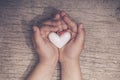 White heart in child hands on old rustic wooden table in vintage retro style Royalty Free Stock Photo