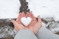 White heart made of snow in women's palms against the background of a forest landscape and a river Royalty Free Stock Photo