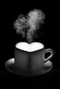 A white heart-shaped mug with a warm drink and curly steam in the shape of a heart on a black background Royalty Free Stock Photo