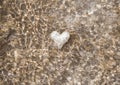 White heart underwater on a sandy beach, sun glare Royalty Free Stock Photo