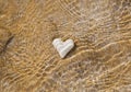 White heart underwater on a sandy beach Royalty Free Stock Photo