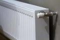 White heating radiator with thermostat valve on wall in an apartment interior after renovation works.