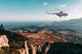 White helicopter flies in mountainous area against sea and blue sky. Search helicopter in flight, rescue people in highlands Royalty Free Stock Photo