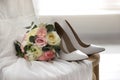 White high heel shoes, flowers and wedding dress on wooden chair indoors Royalty Free Stock Photo