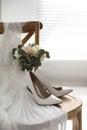 White high heel shoes, flowers and wedding dress on wooden chair Royalty Free Stock Photo