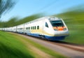 White high speed railway train runs on rail tracks among green trees. Train in motion. Motion blur Royalty Free Stock Photo